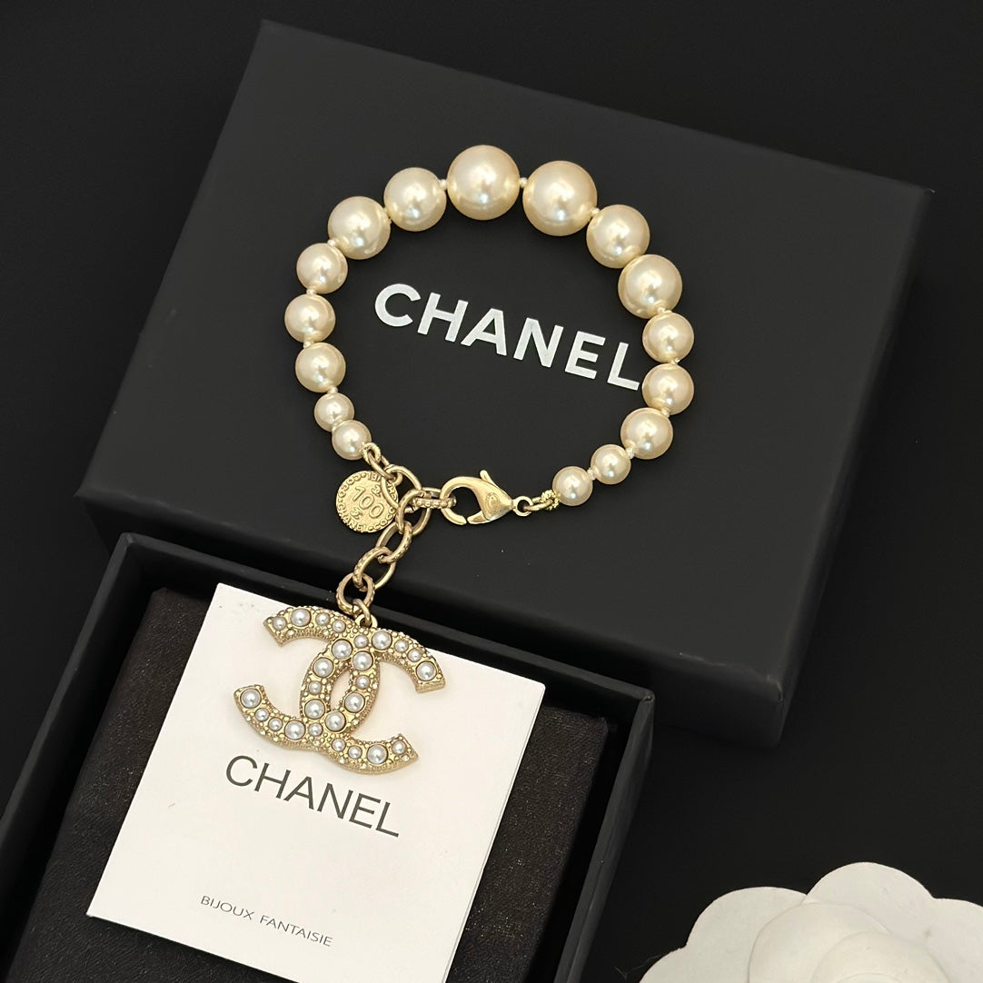 Chanel pearl bracelet with gold-tone chain and dangling logo charm