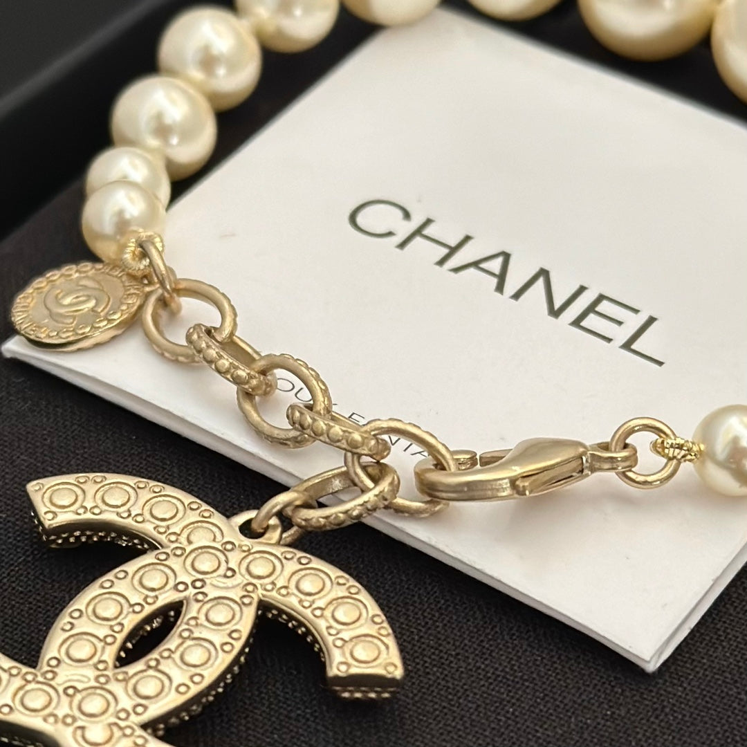 Chanel pearl bracelet close-up with gold-tone chain and logo charm medallion