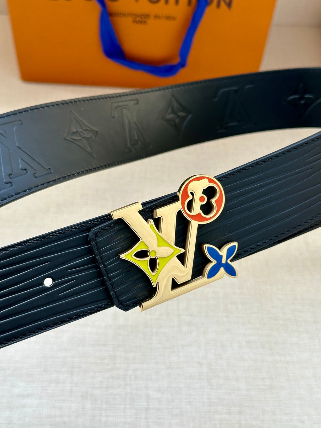 Louis Vuitton belt buckle close-up with multicolor charms on dark leather strap