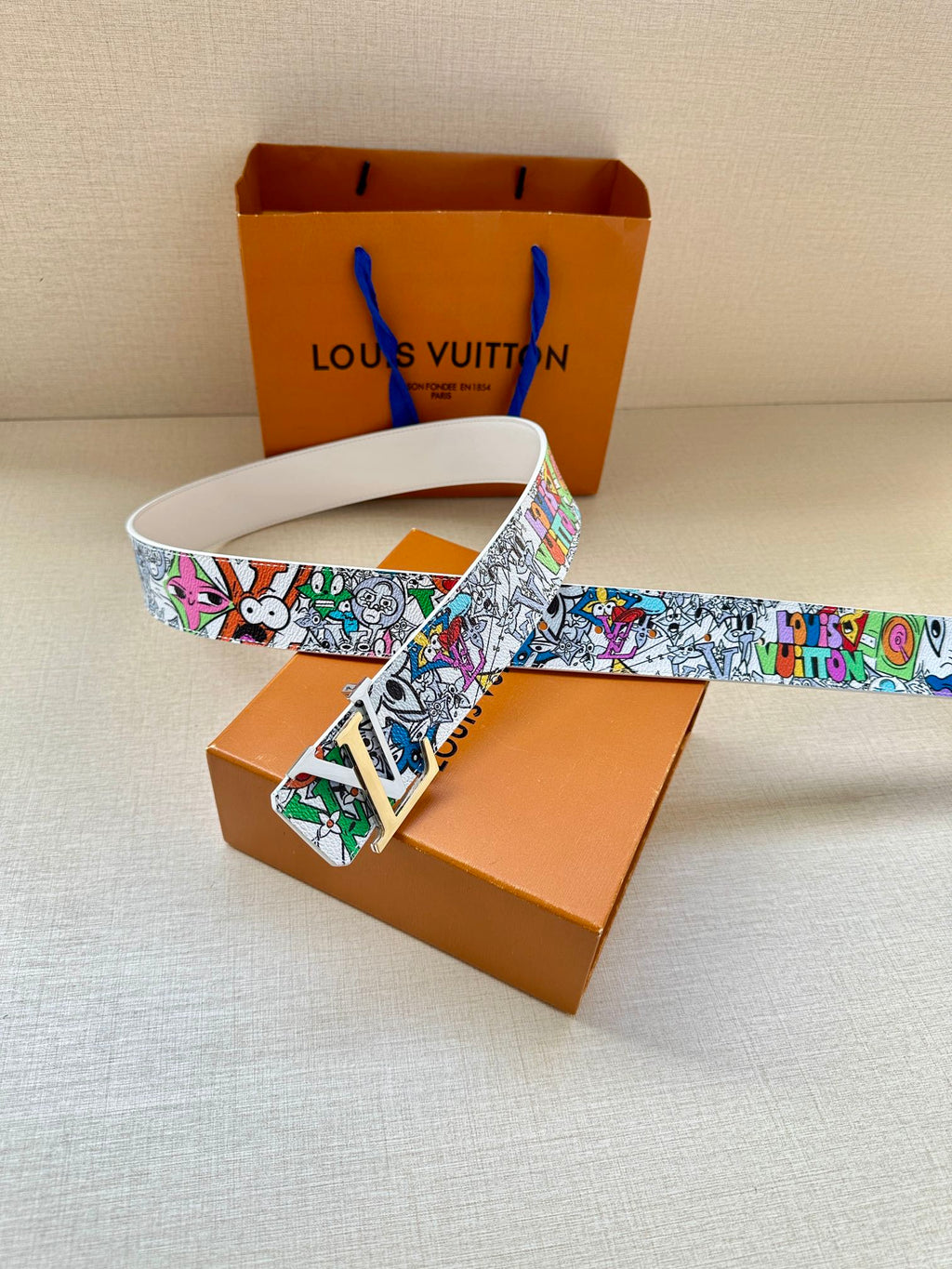 White leather belt with multicolor graffiti strap and gold-tone buckle