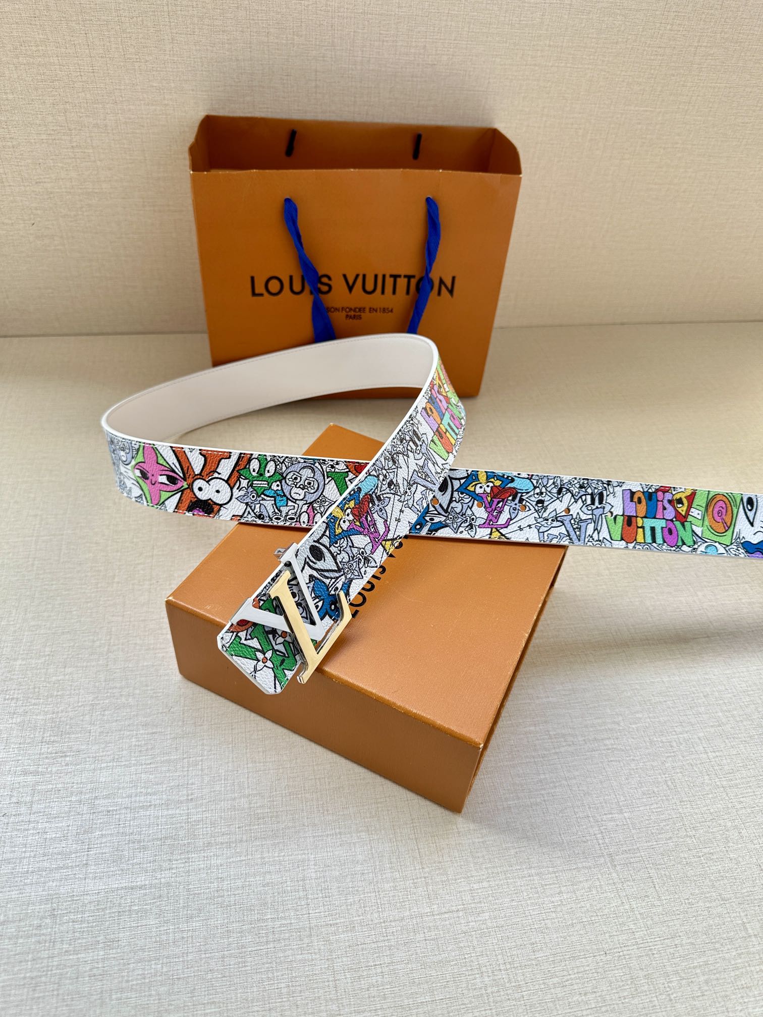 White leather belt with multicolor graffiti strap and gold-tone buckle