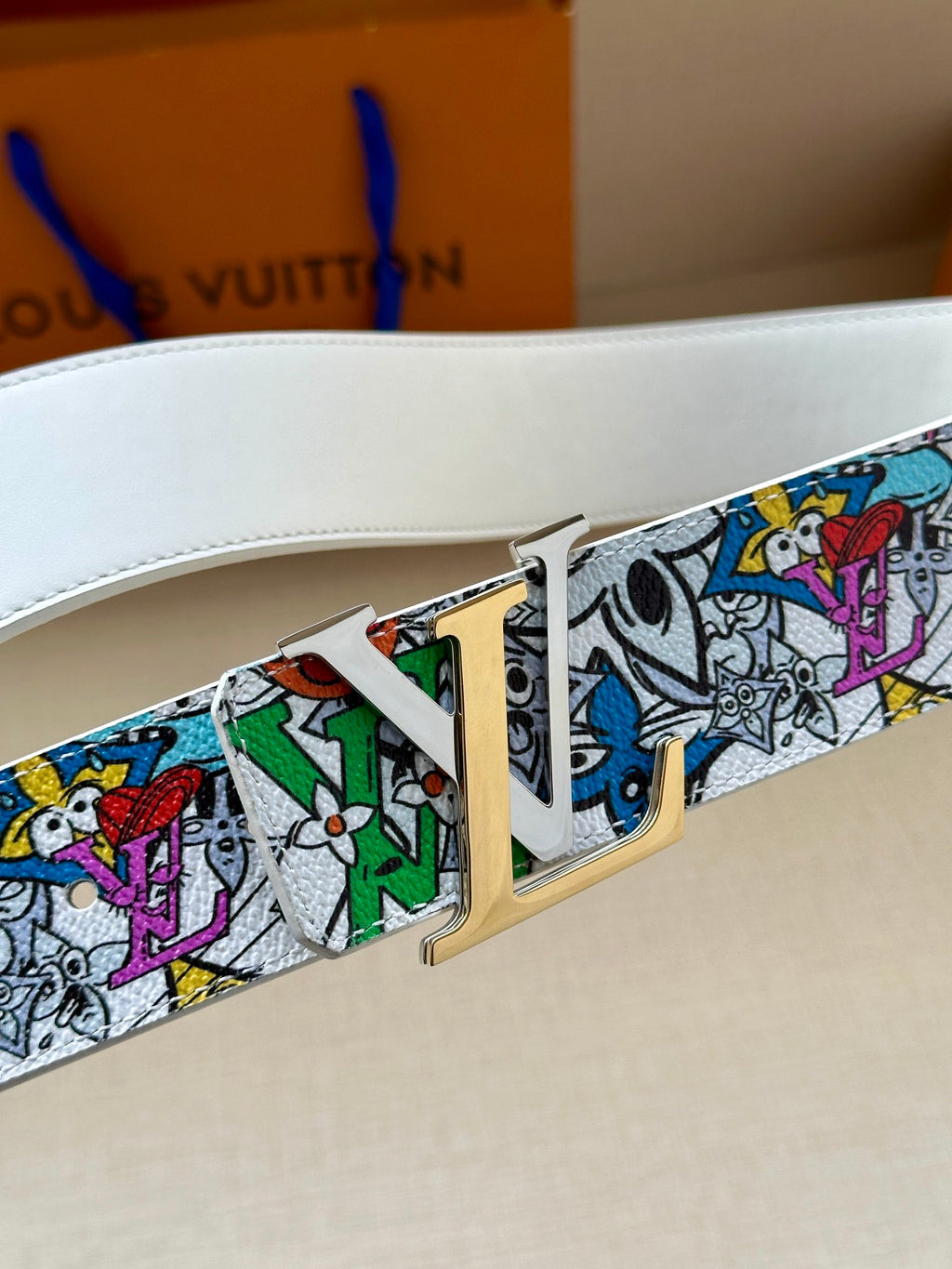 Belt buckle close-up on white strap with multicolor graphic print