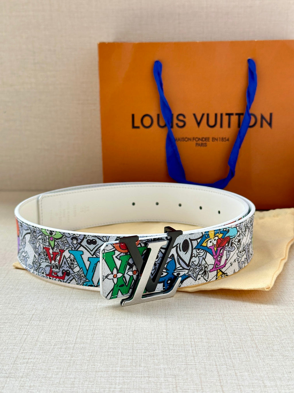 Belt on white strap with multicolor graphic band and gold-tone buckle