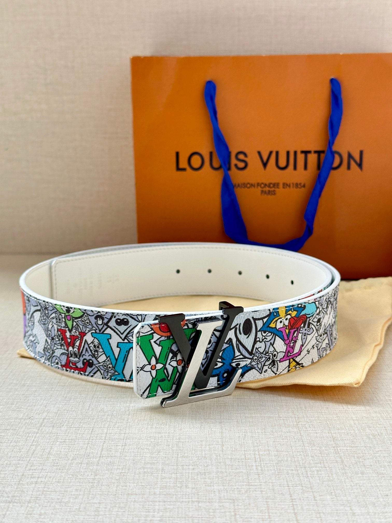 Belt on white strap with multicolor graphic band and gold-tone buckle