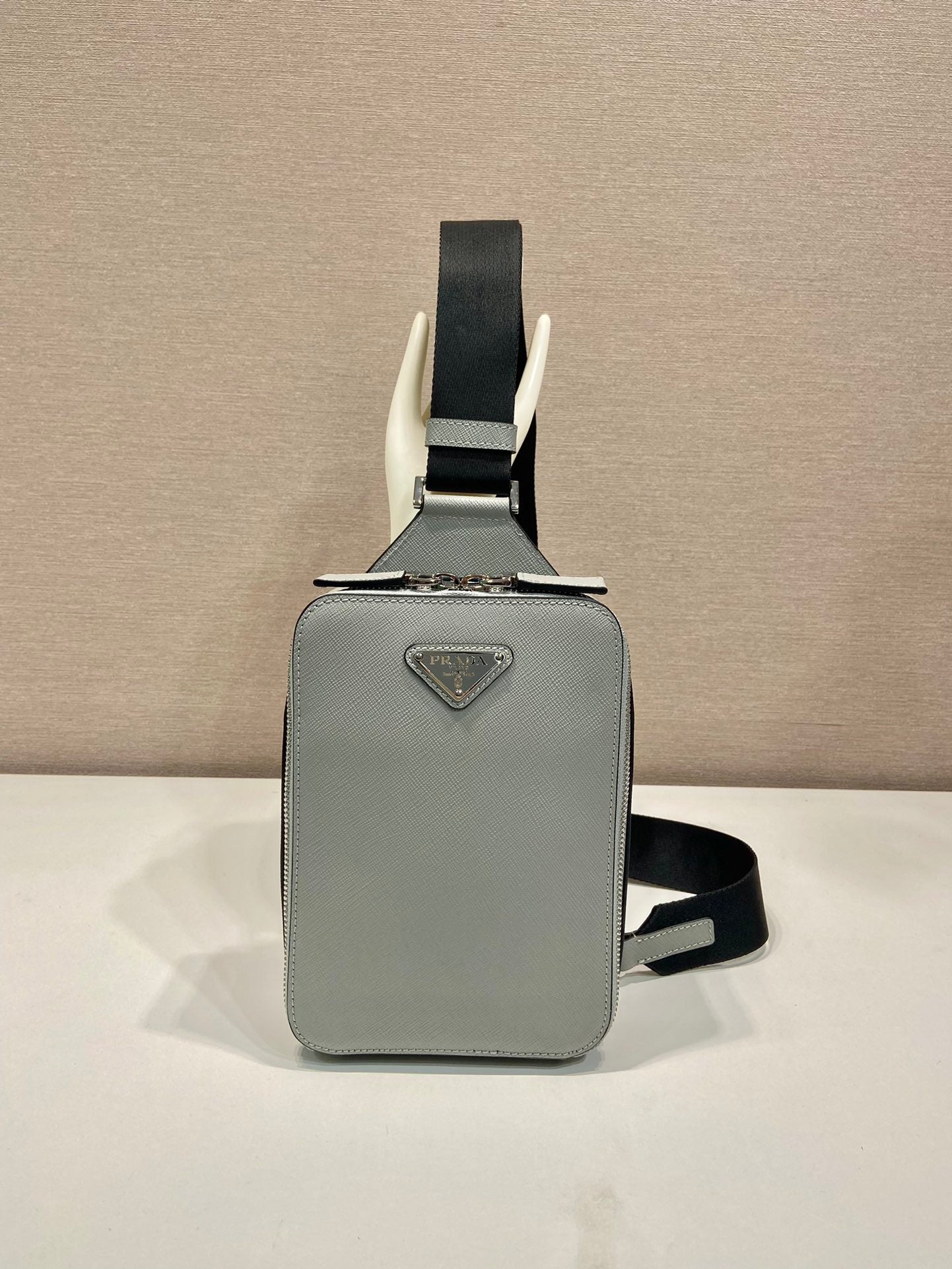 Prada mini crossbody bag, light gray with black strap and triangular logo plaque