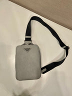 Prada mini crossbody bag, light gray with black shoulder strap, overhead view