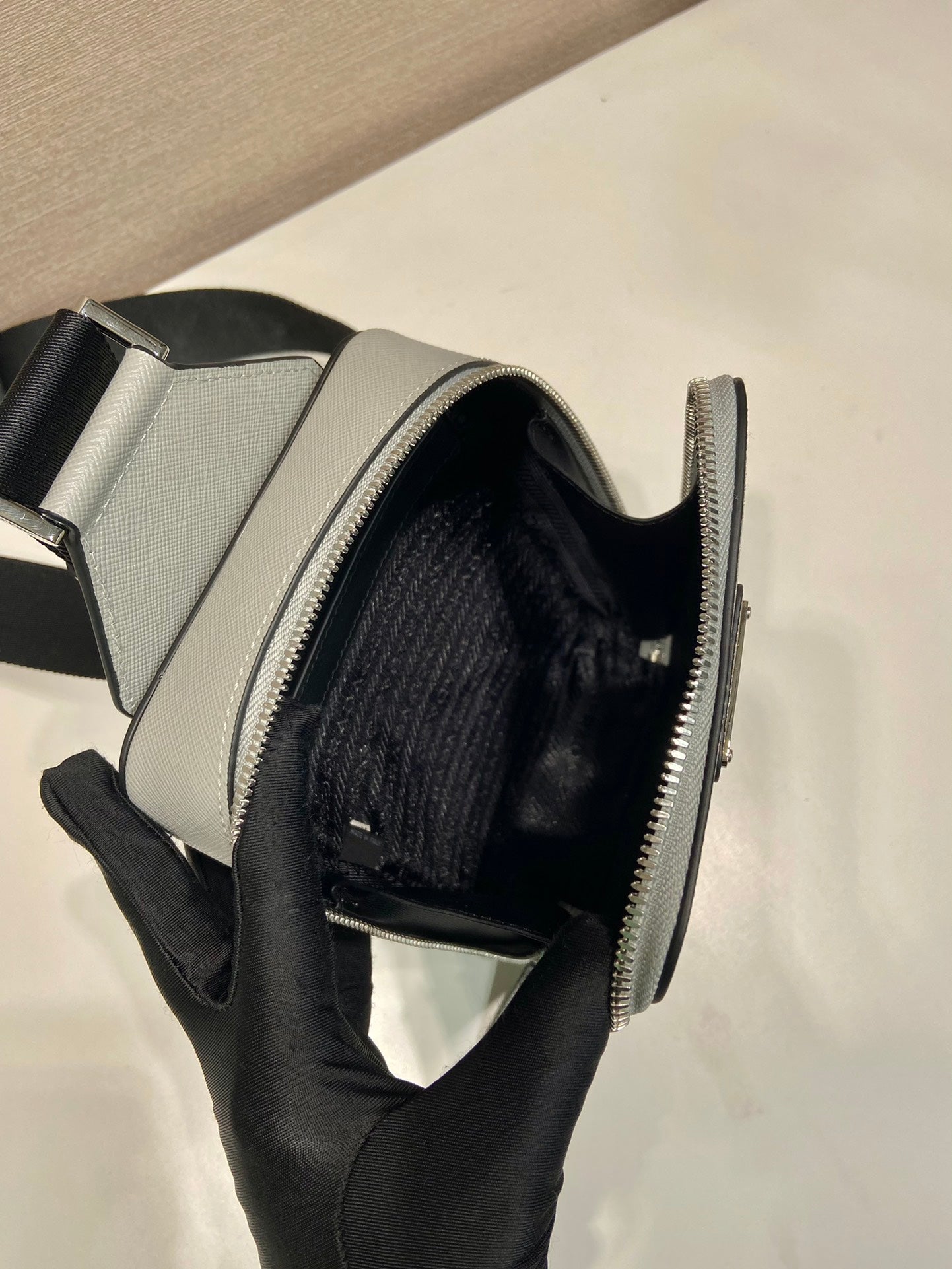 Prada mini bag interior, light gray exterior with black-lined main compartment