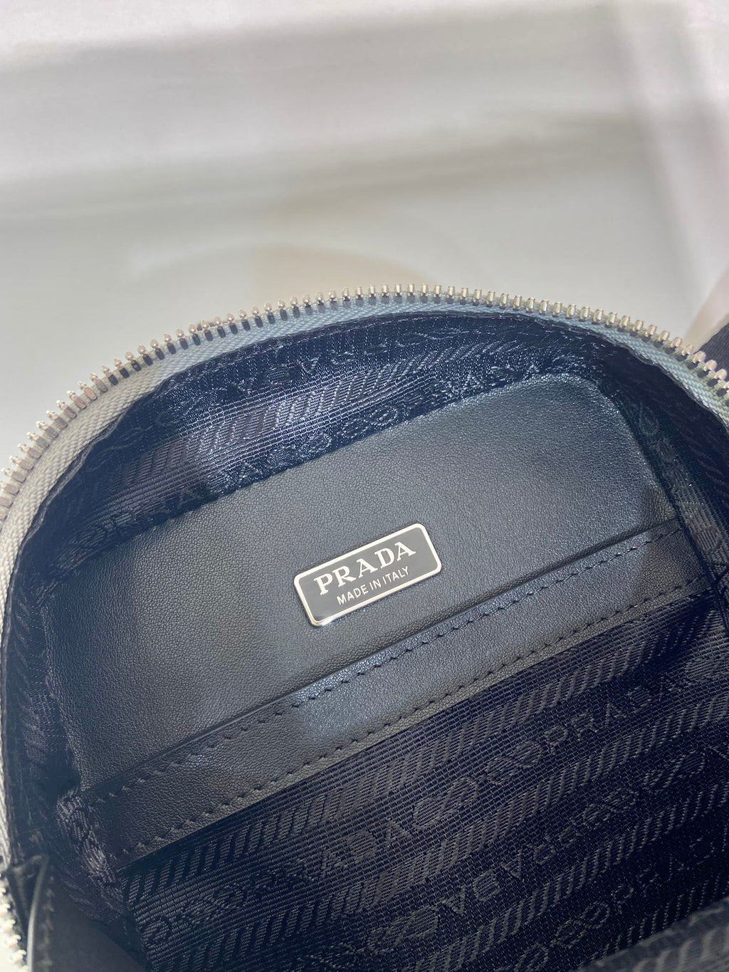 Prada mini bag lining close-up, navy patterned fabric with Prada logo patch