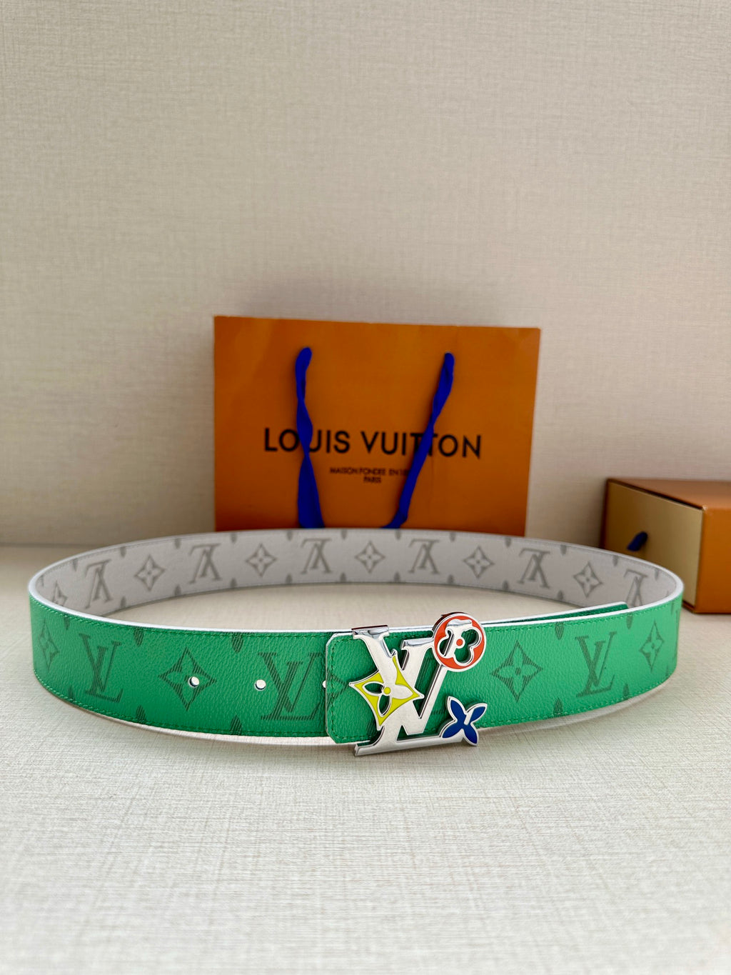 Louis Vuitton belt with green monogram strap and silver buckle with colorful charms