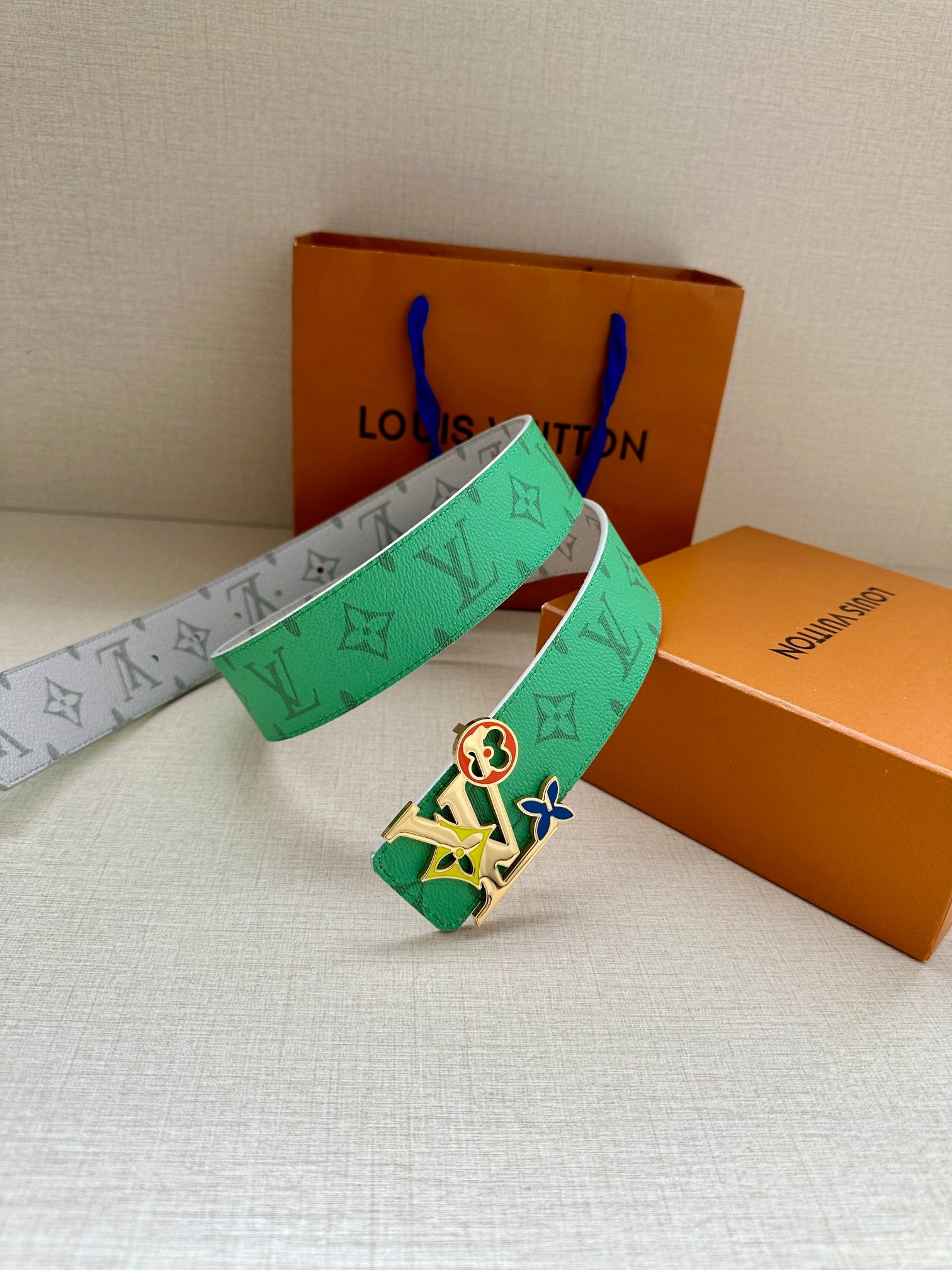Louis Vuitton belt with green monogram strap and silver buckle, belt ends crossed