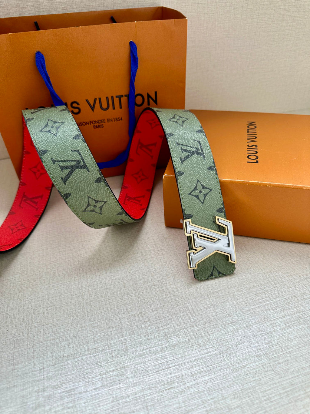 Louis Vuitton belt laid out with green monogram strap and silver-tone LV buckle