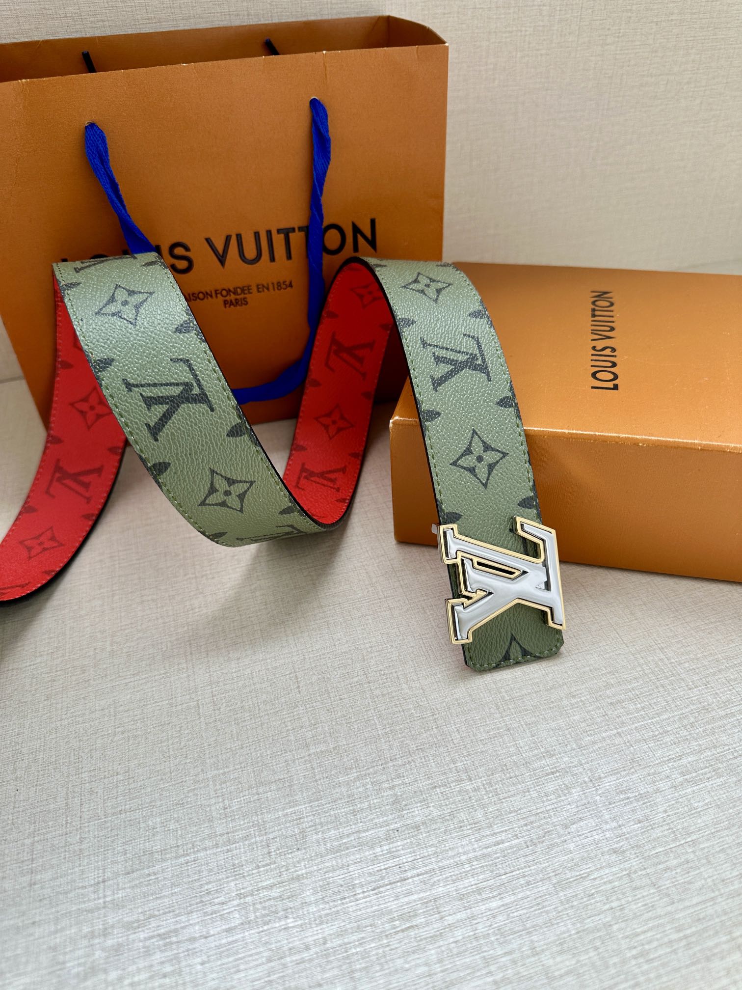 Louis Vuitton belt laid out with green monogram strap and silver-tone LV buckle