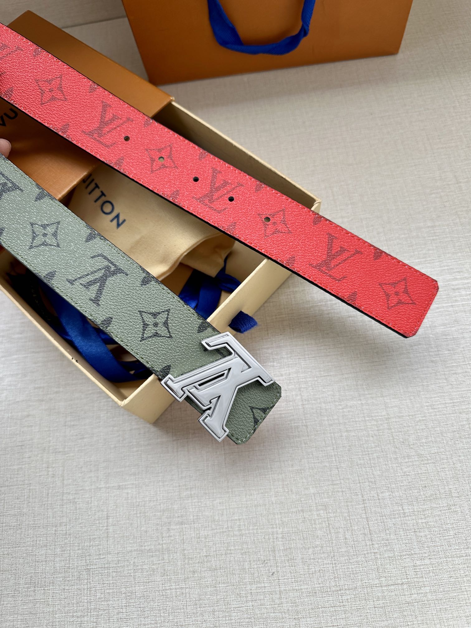 Louis Vuitton belt straps in box: red underside strap and green monogram strap with buckle