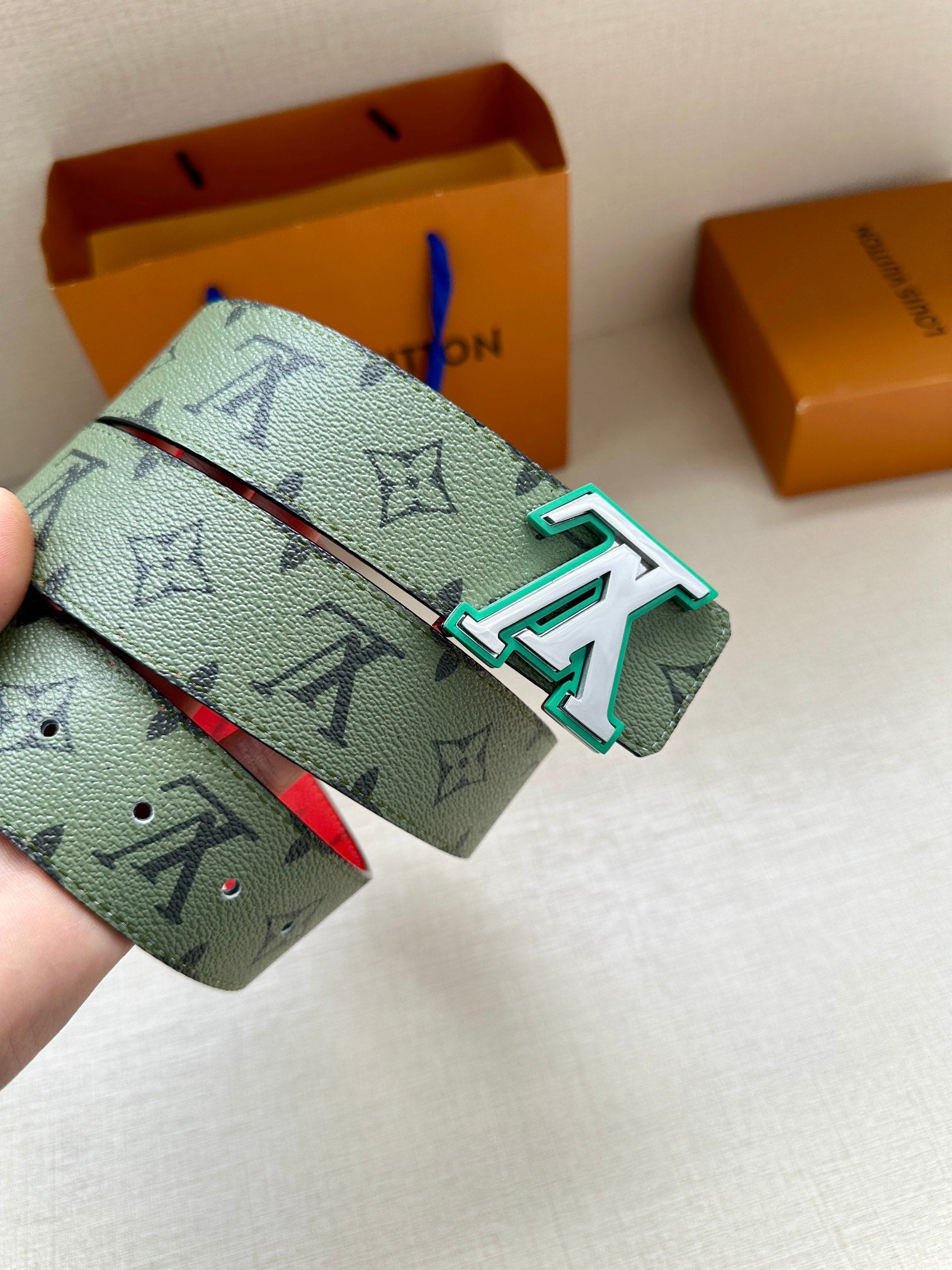 Louis Vuitton belt end with green monogram strap and silver buckle with teal accents