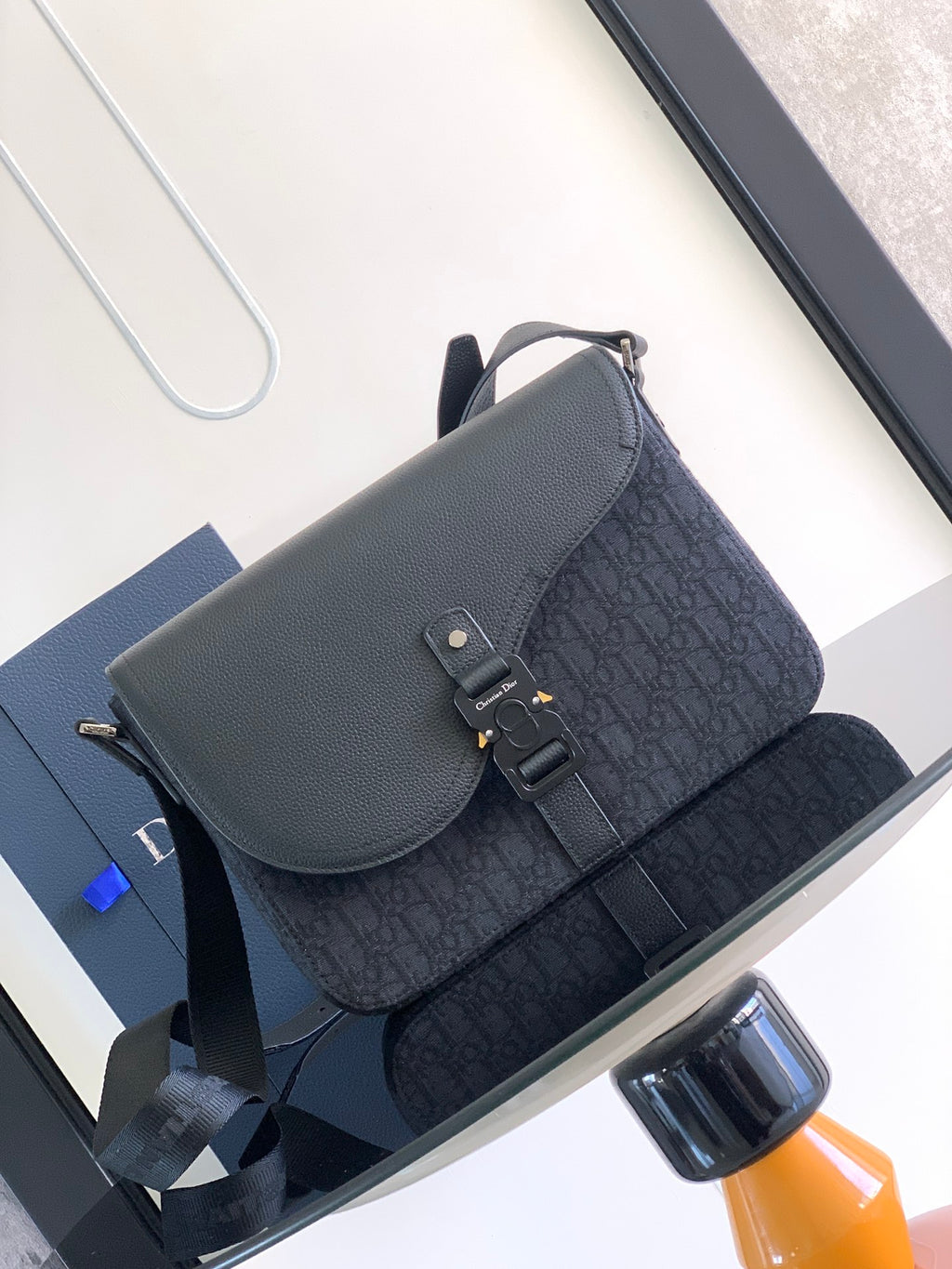 Dark crossbody bag with flap, patterned front panel, and adjustable shoulder strap