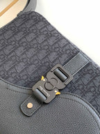 Close-up of dark crossbody bag hardware and textured fabric strap