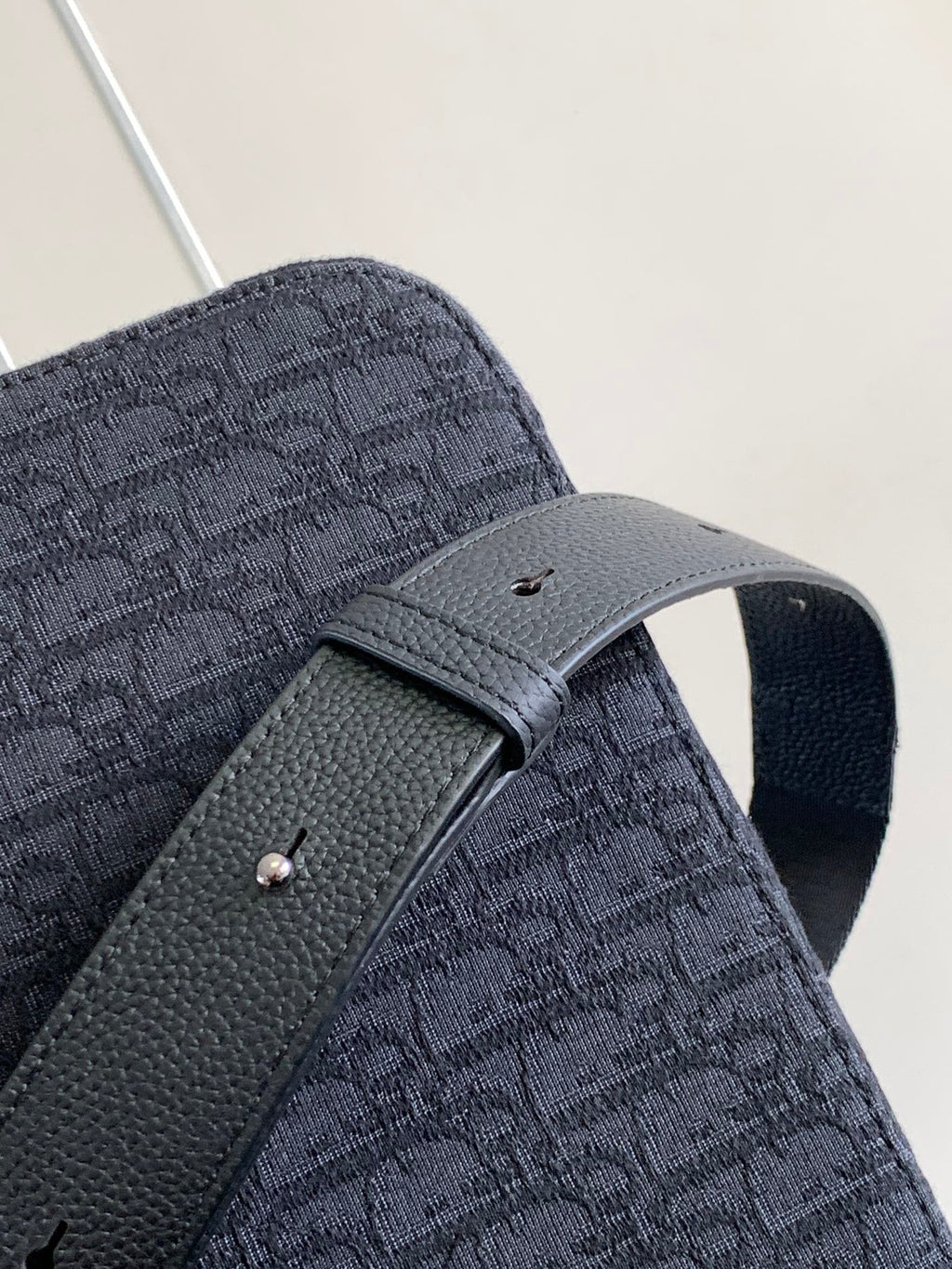 Dark crossbody bag with front strap and textured fabric flap detail