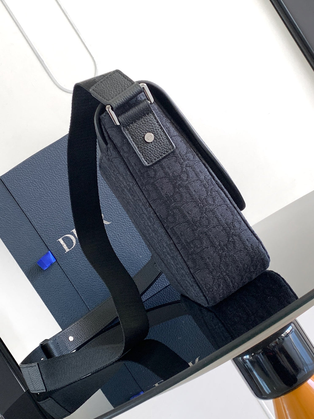 Dark crossbody bag with flap and textured body, shown with side strap