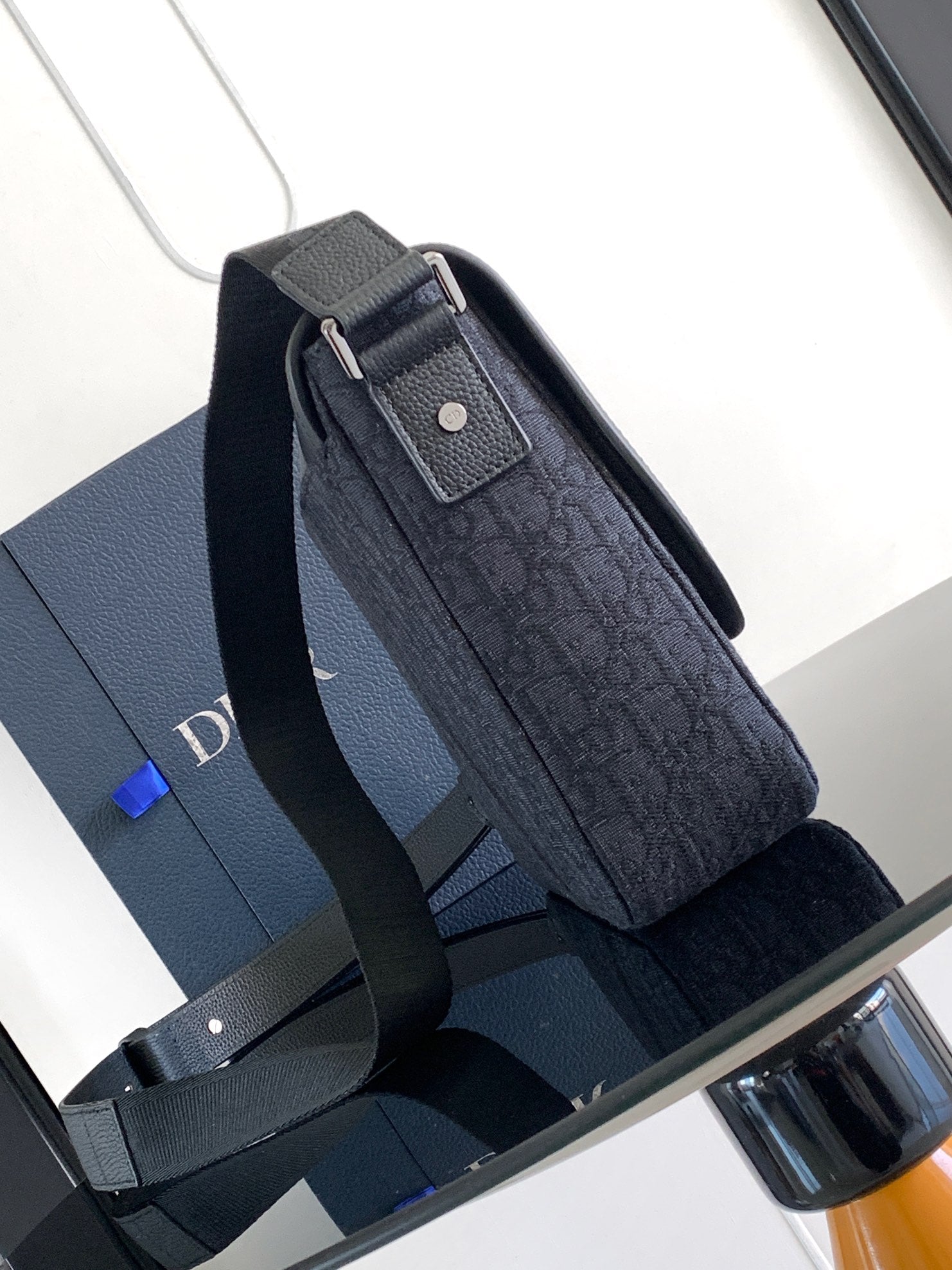 Dark crossbody bag with flap and textured body, shown with side strap