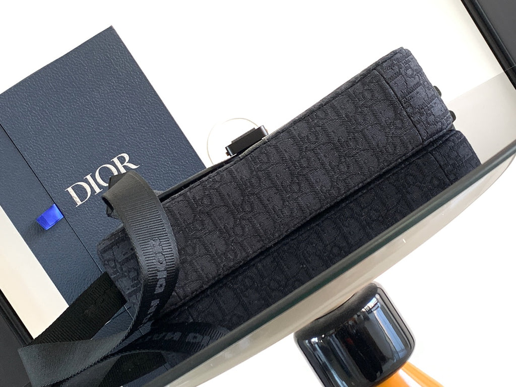 Dark crossbody bag with long front flap and textured pattern, secured with hardware