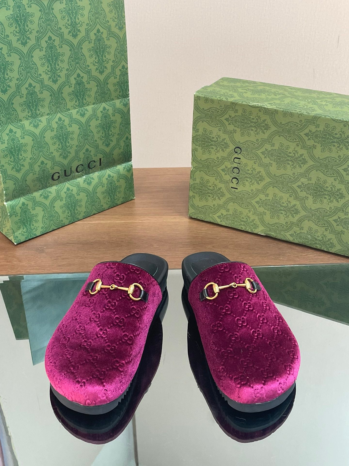 Two pink velvet slide sandals with gold horsebit hardware, black base
