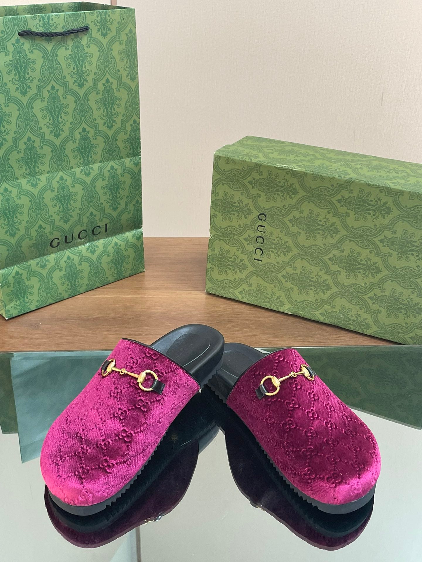 Pair of pink velvet slide sandals with gold horsebit, black soles