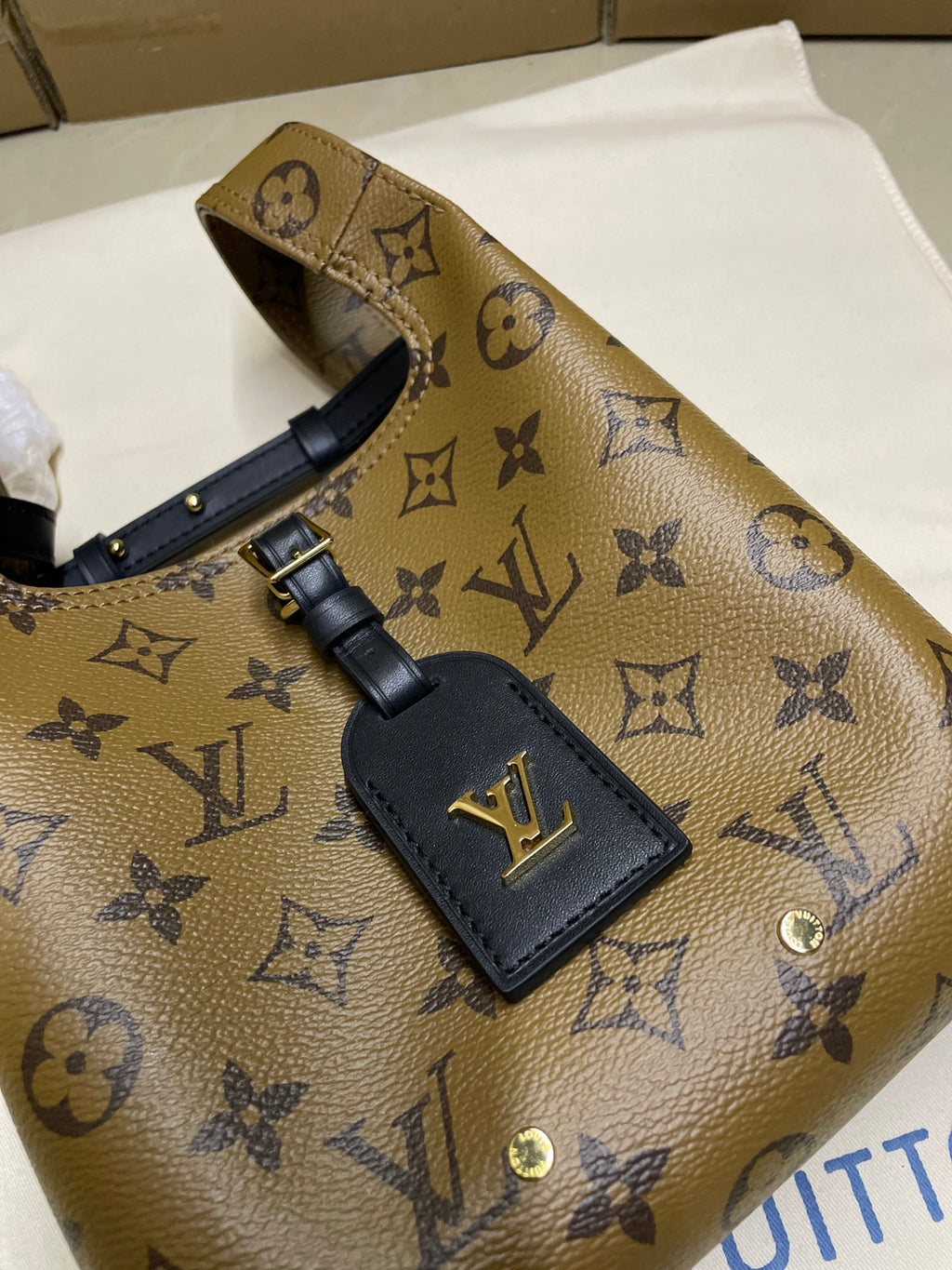 Louis Vuitton monogram handbag with navy front leather patch and gold emblem hardware