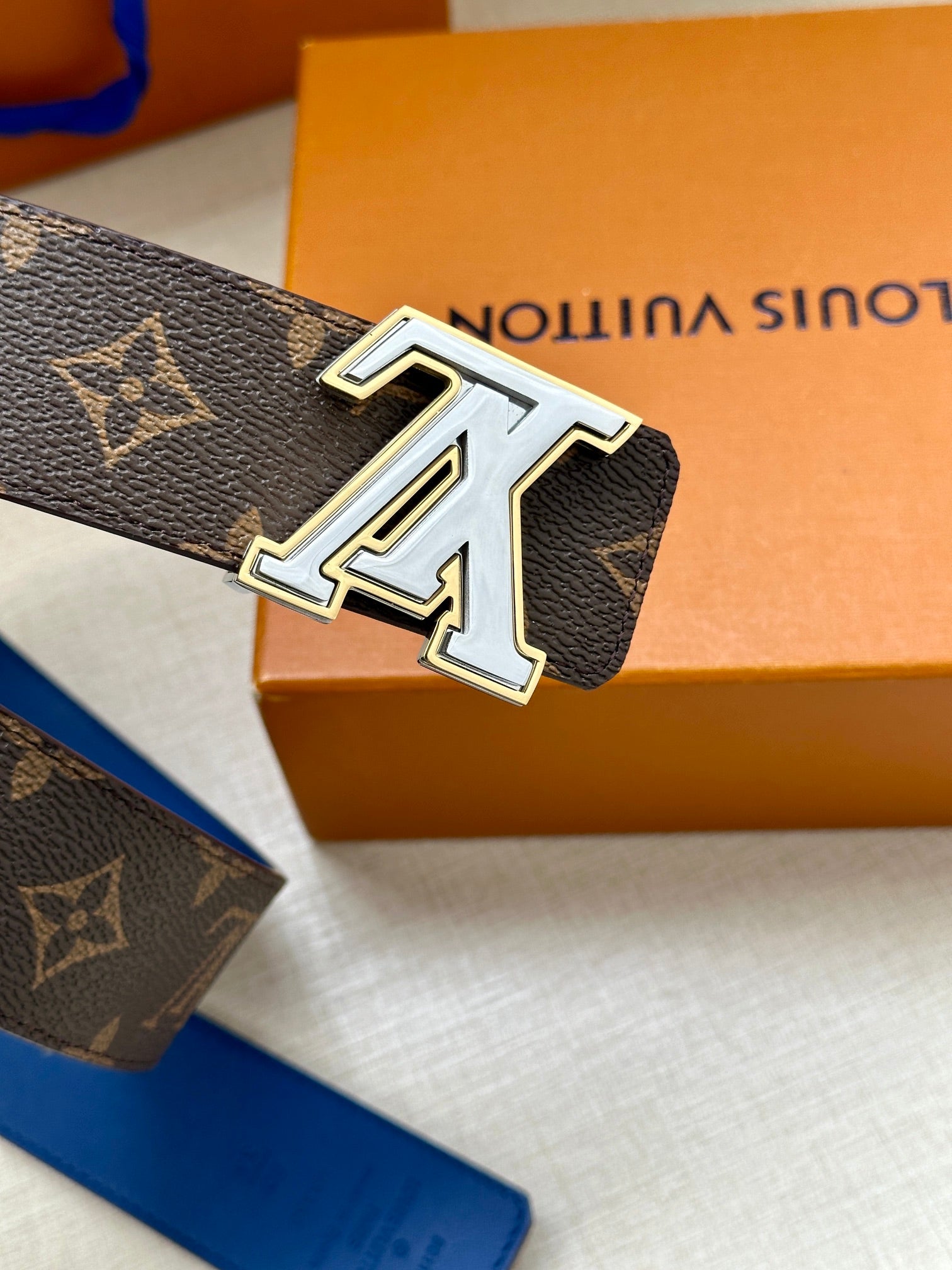 Louis Vuitton monogram belt close-up showing silver LV buckle on dark canvas