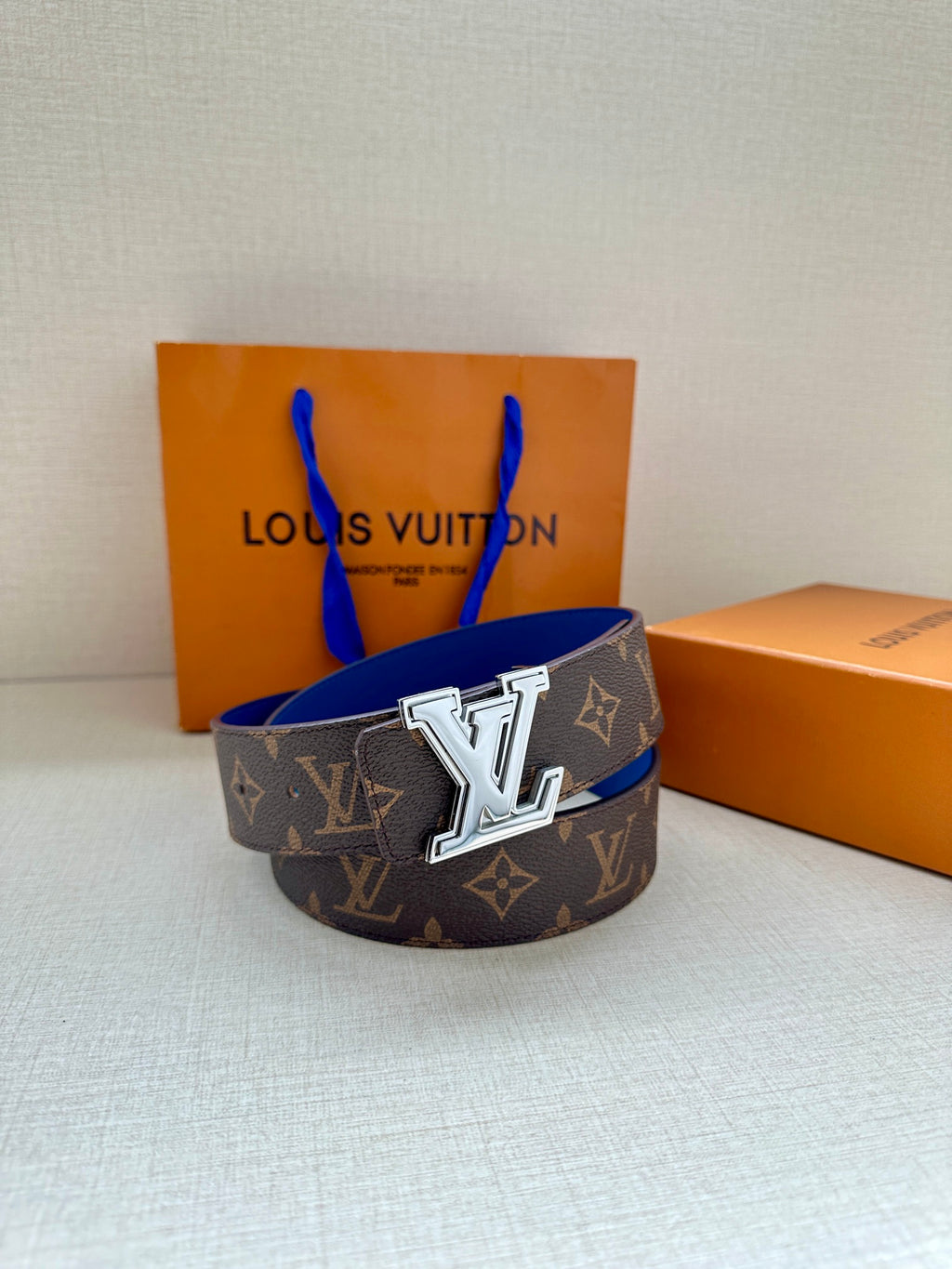 Louis Vuitton monogram belt featuring dark canvas and blue leather strap with silver LV buckle