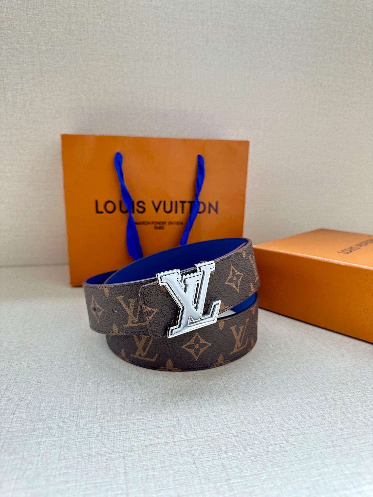 Louis Vuitton monogram belt featuring dark canvas and blue leather strap with silver LV buckle