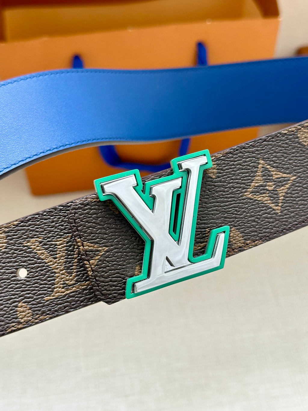 Louis Vuitton belt detail: dark monogram canvas band with blue edge and LV buckle