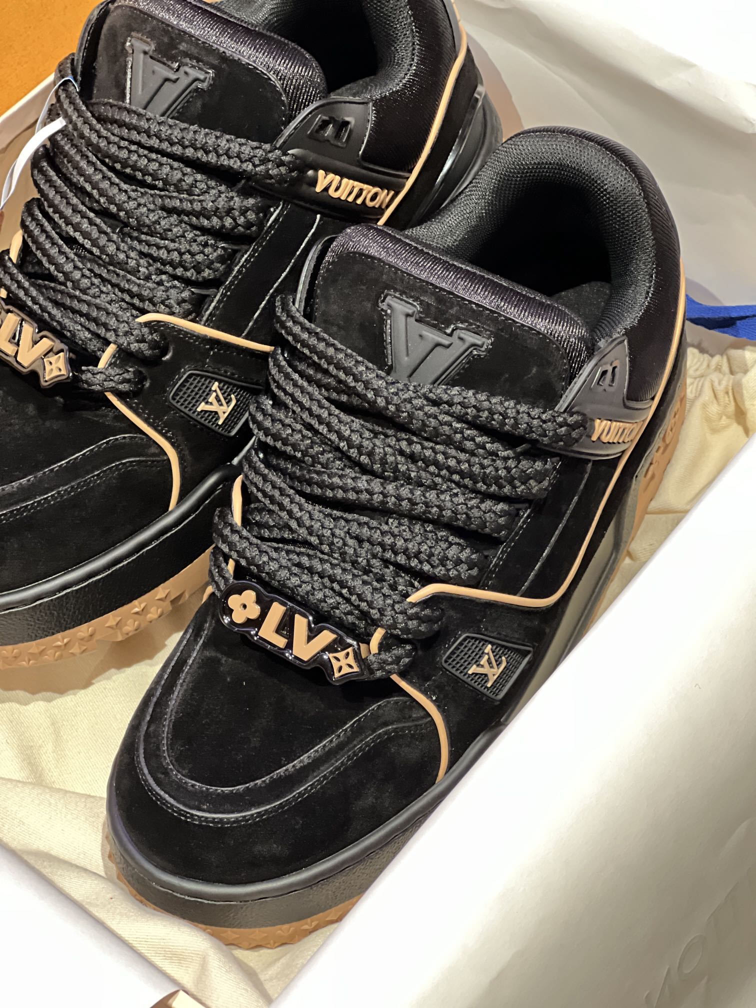 Louis Vuitton trainer shoes close-up, black suede with embossed LV patch and laces