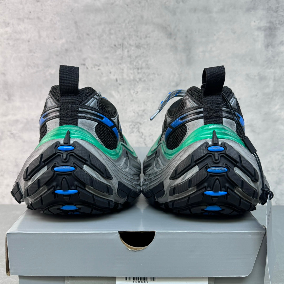 Unisex sneakers rear view on box, black uppers with blue accents and green midsole stripe.