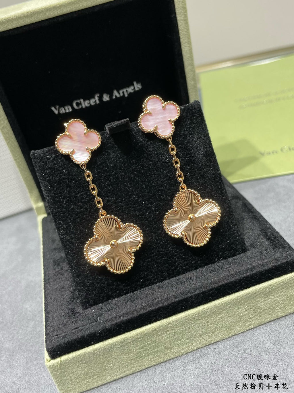 Gold-tone dangling earrings with pink four-leaf clover tops and flower drop charms