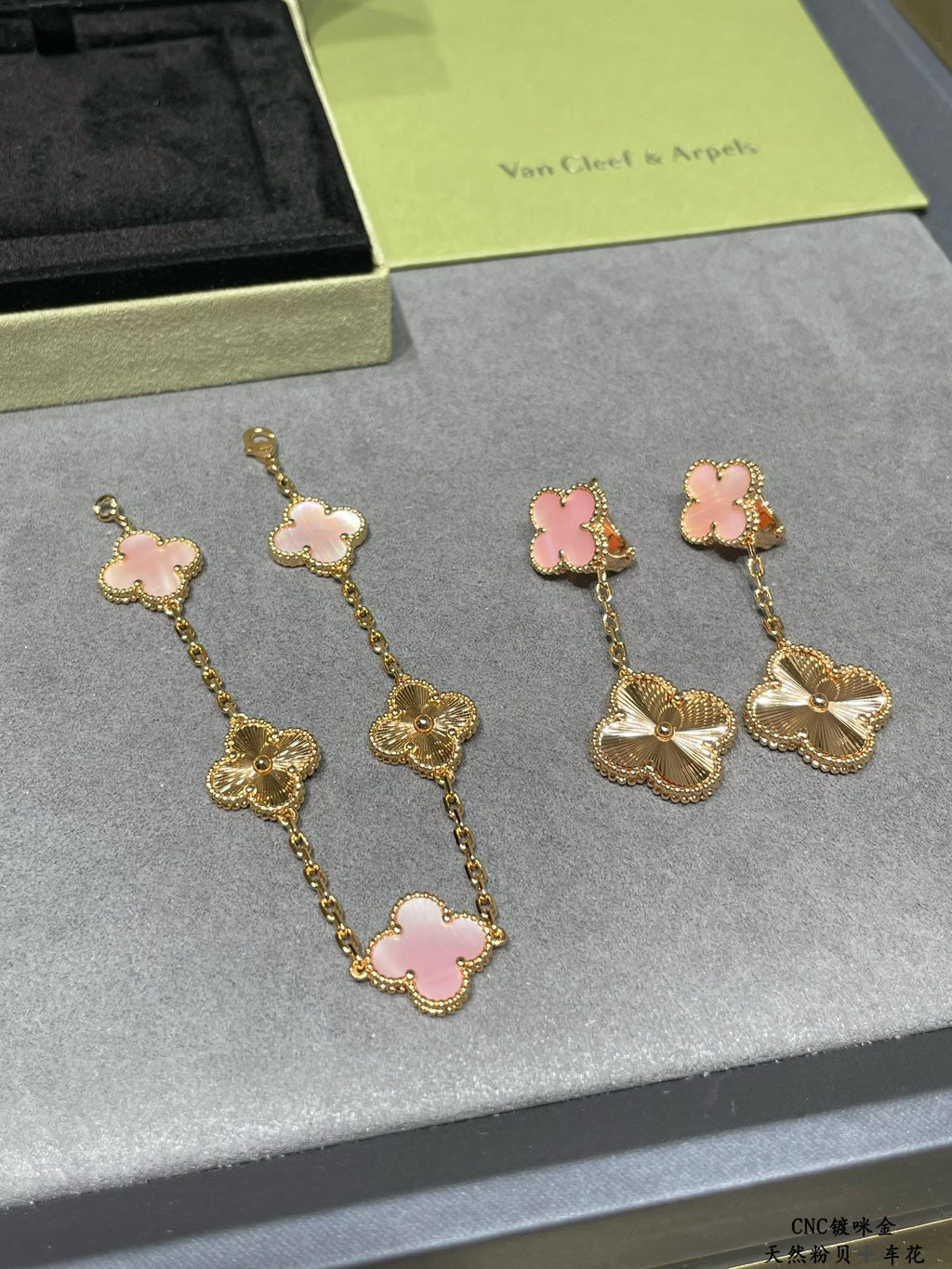 Gold-tone earrings with pink clover enamel and long chains ending in scalloped flower charms