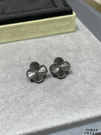 Pair of silver-tone quatrefoil stud earrings on gray display