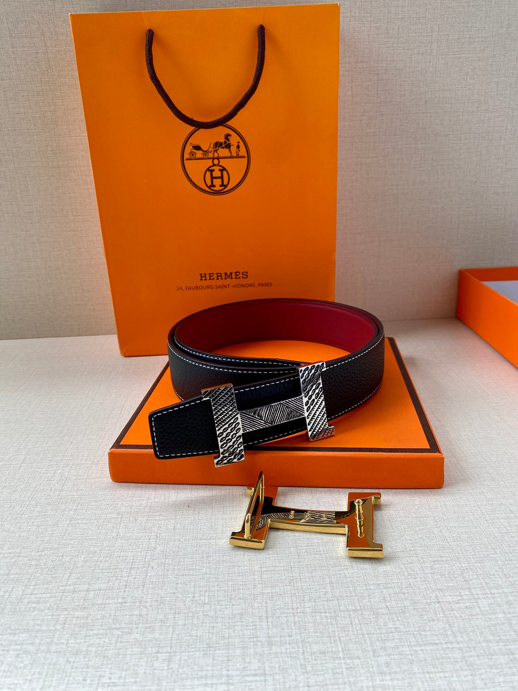 Hermes belt with dark blue strap, red lining, and silver-tone hardware on box