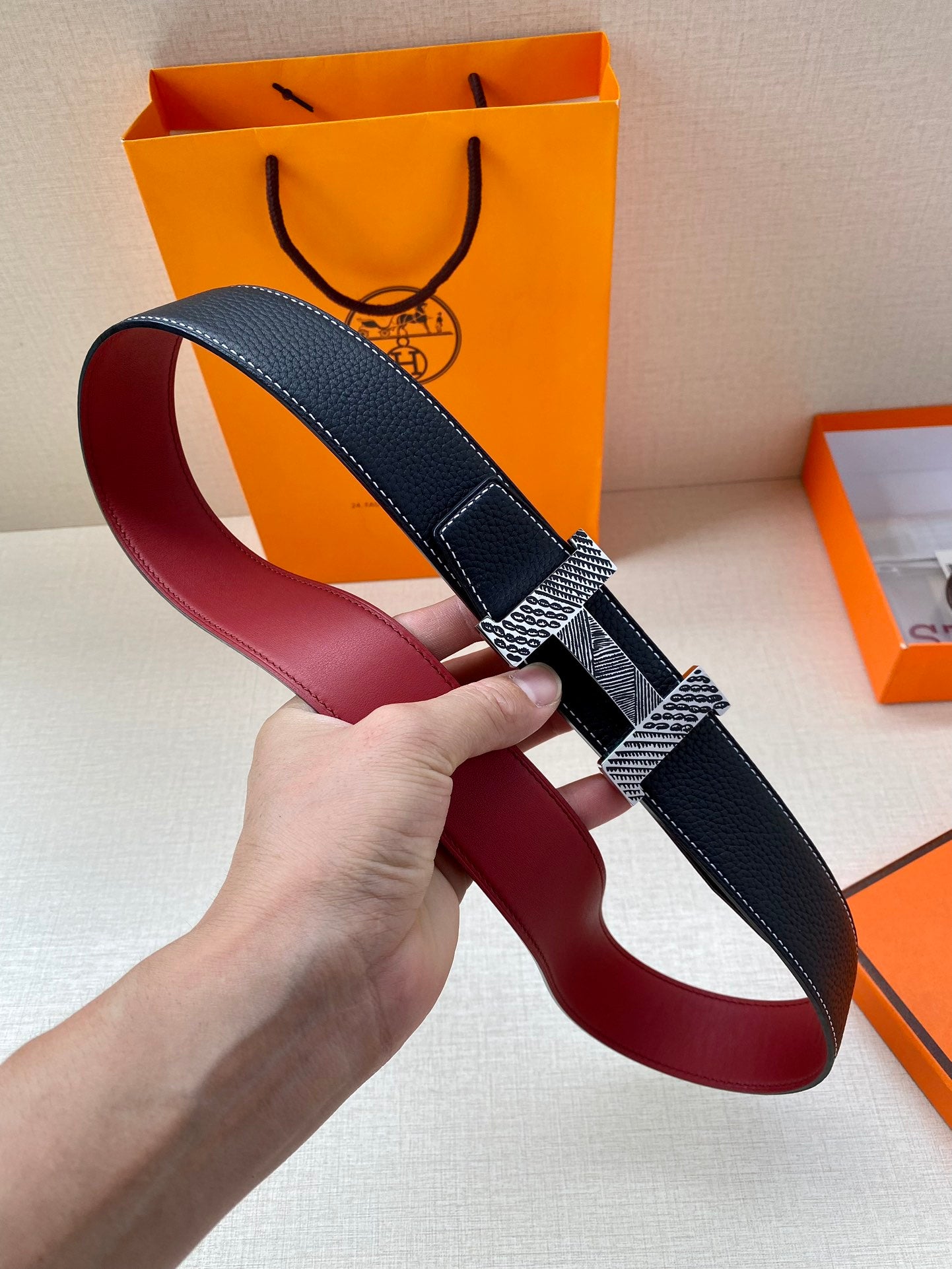 Hermes belt with dark blue strap and red underside, buckle with gold patterned insert