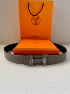 Grey leather belt with dark interior and textured gold-tone buckle, laid flat.