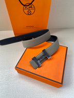 Grey leather belt with textured gold-tone buckle, side view with strap crossing.