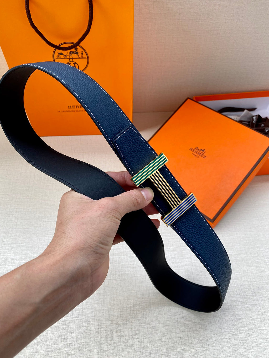 Blue leather belt looped, striped green-and-gold buckle at center