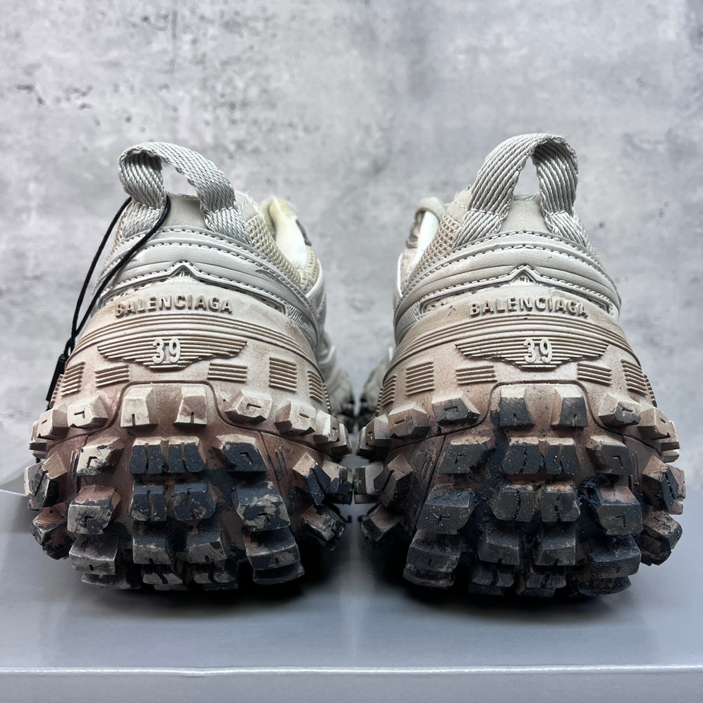 Unisex sneakers heel view, thick lug soles and light gray uppers with lace-up ties.
