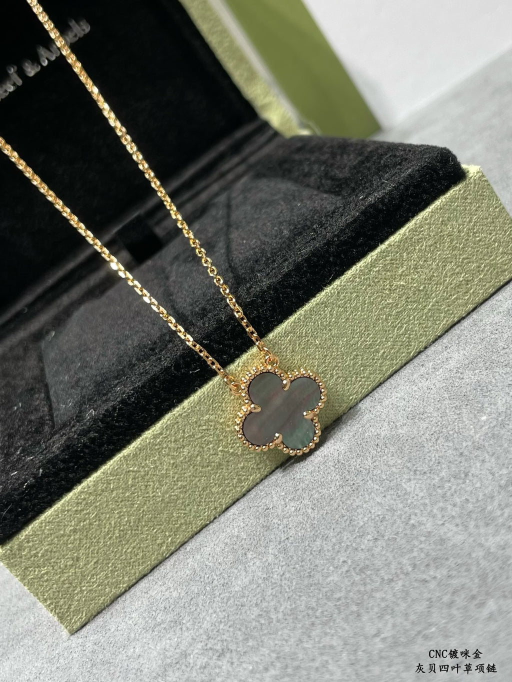 Van Cleef & Arpels accessories: gold clover pendant necklace on black velvet insert