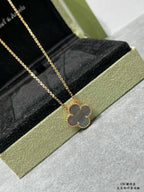 Van Cleef & Arpels accessories: gold clover pendant necklace on black velvet insert