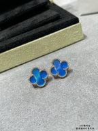 Pair of blue clover stud earrings with gold-tone frames on gray surface