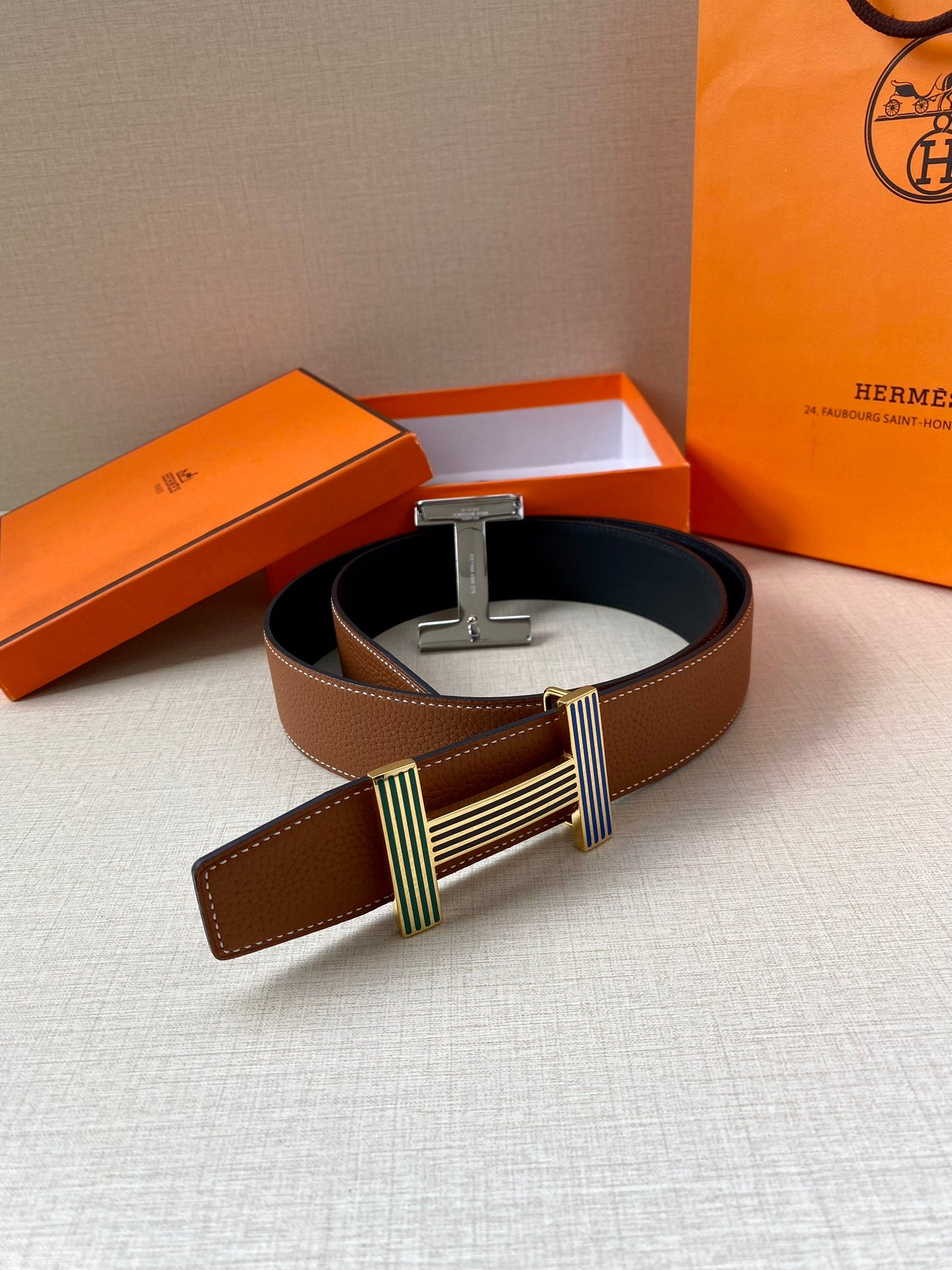 Brown leather belt with wide silver-tone buckle and striped green and blue accents