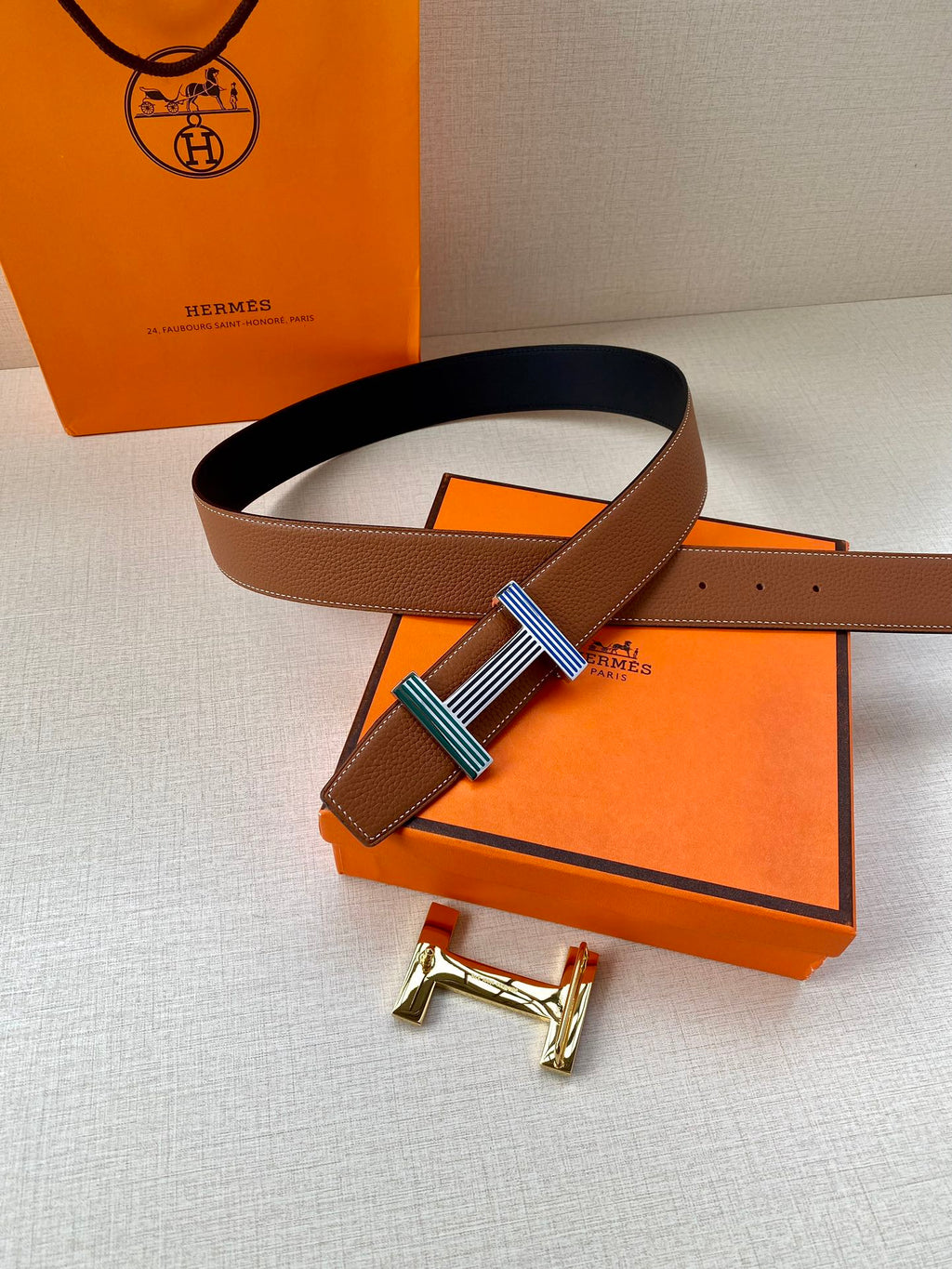 Brown leather belt with striped buckle and matching belt loops on dark underside strap