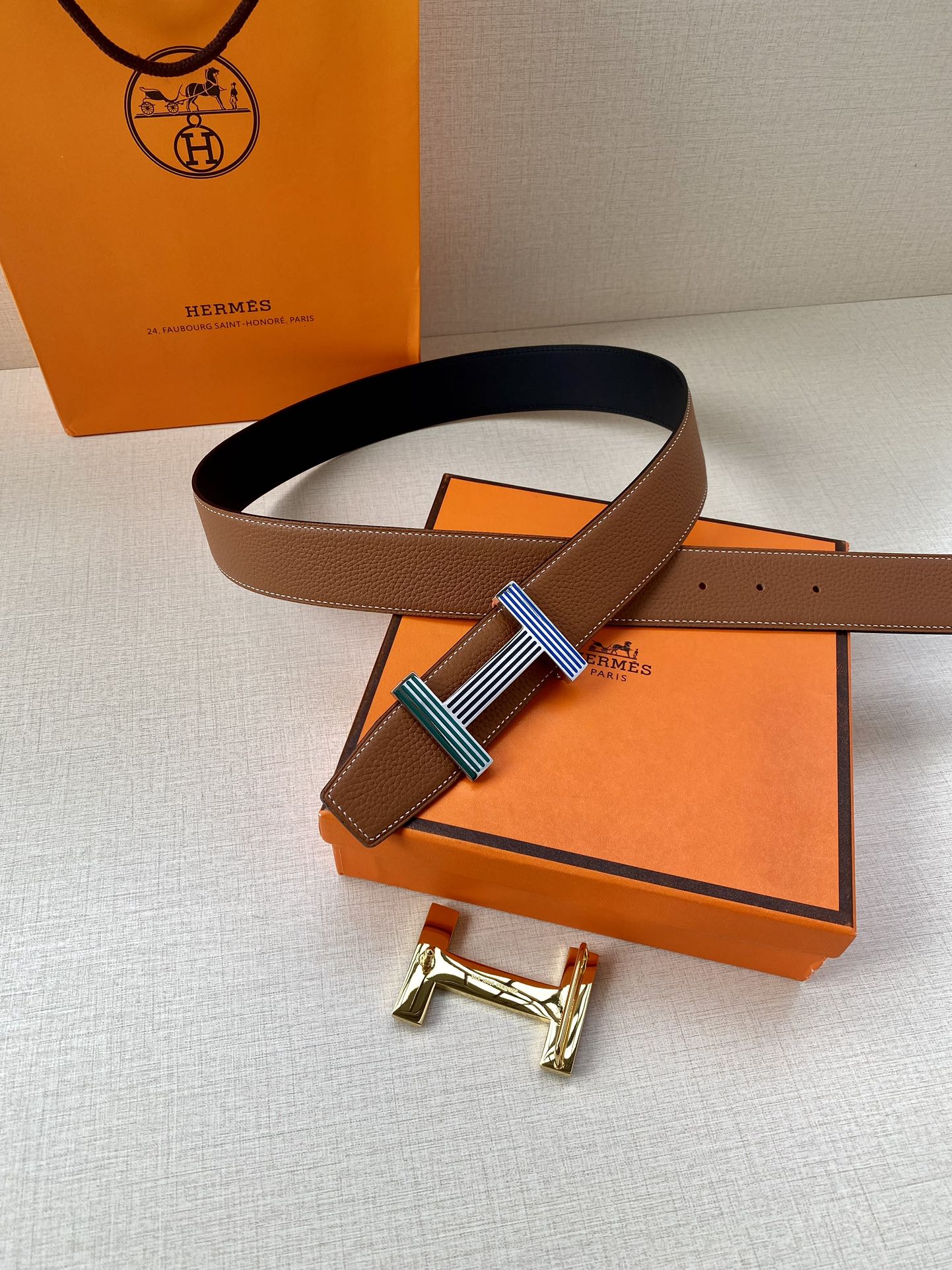 Brown leather belt with striped buckle and matching belt loops on dark underside strap