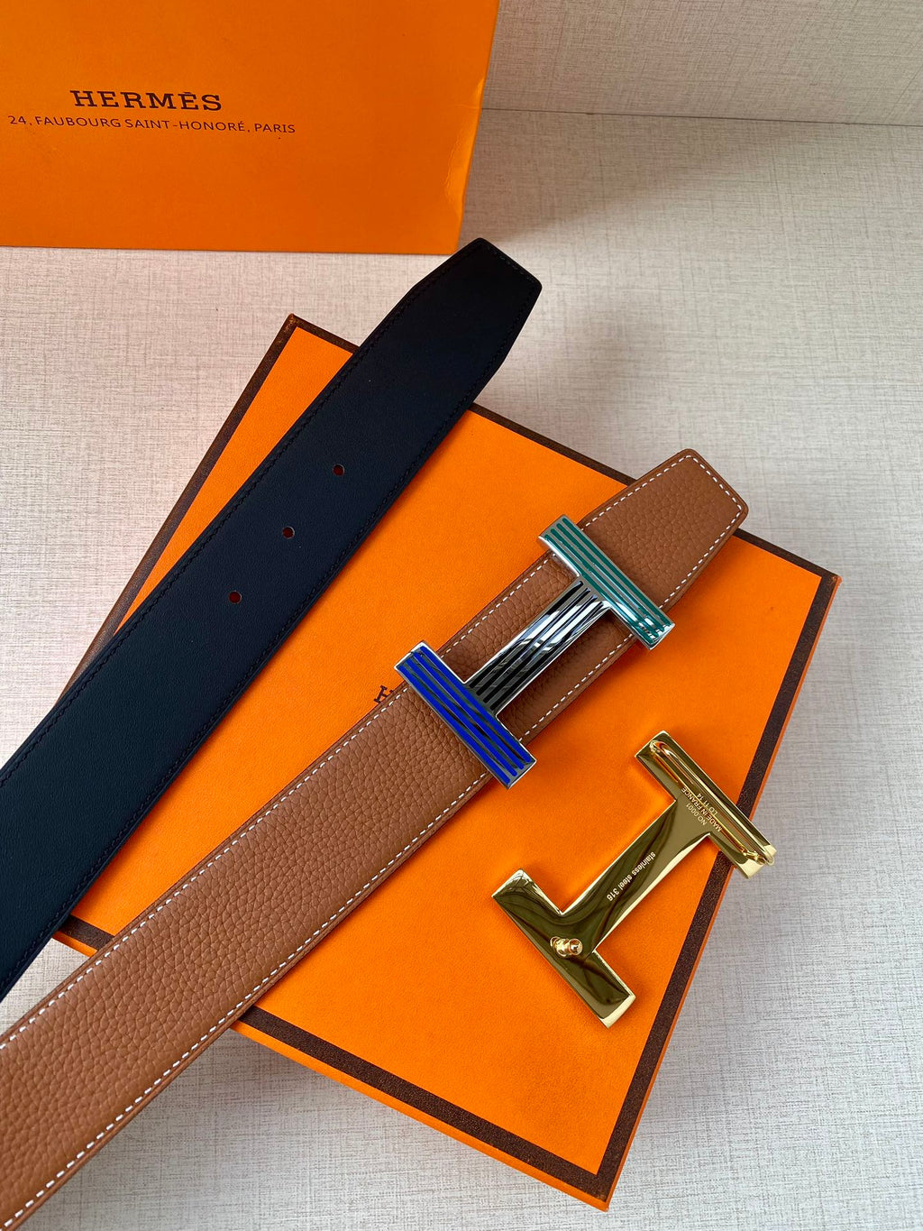 Brown leather belt with navy strap and striped buckle with silver-tone hardware
