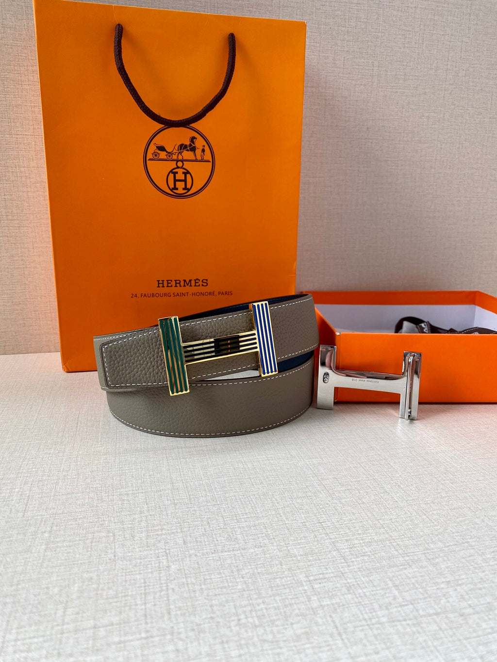 Hermes belt gray leather with striped buckle and gold buckle hardware on display